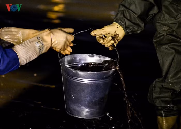 Bùn đất, rác thải được đựng trong các xô nhỏ và theo băng chuyền tay đưa lên bờ