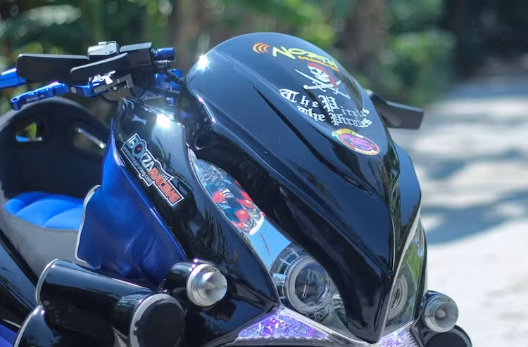 Dựa trên chiếc PCX thế hệ đầu tiên, bộ đèn pha của xe đã được độ lại với cặp đèn dạng thấu kính projector như "mắt cú". Phần trước của xe còn được ốp mặt nạ khiến đèn pha đơn của PCX trông như một cặp pha kép giống "đàn anh" Honda Forza 250. Bộ mâm 5 cánh kép xoắn trên bản độ này được giữ nguyên, nhưng có hệ thống phanh trước độ lại với đĩa kiểng.