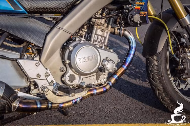 Nằm hai bên khối động cơ SOHC 4 van 150 cc nguyên bản của FZ150i là cặp chống đổ kèm đèn LED trợ sáng. Động cơ của xe cũng có hệ thống xả được làm từ titan và gia nhiệt ánh xanh nổi bật.