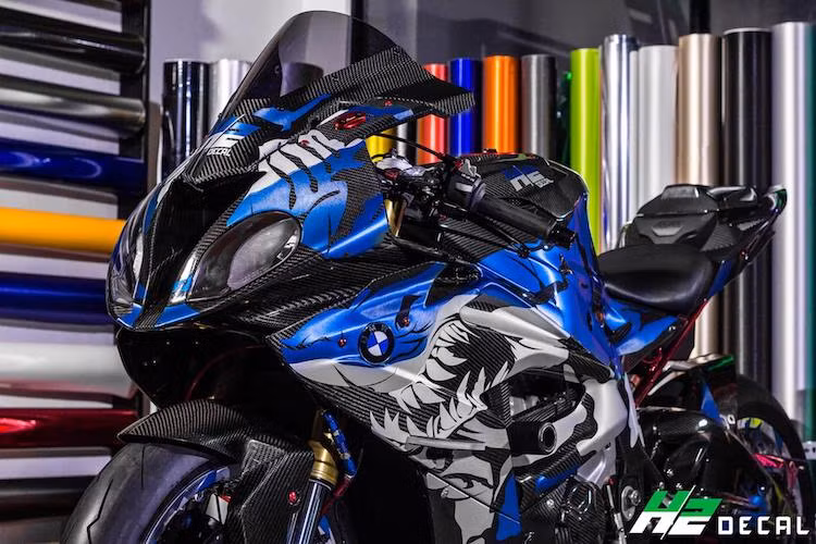 Mới đây, một biker miền Tây đã cho "ra lò" bản độ S1000RR có thể nói là độc nhất Việt Nam khi sở hữu vẻ ngoài ấn tượng và được trang bị nhiều phụ tùng đắt giá. Trong đó, toàn bộ dàn vỏ nguyên bản của chiếc xe đã được thay bằng vỏ carbon của hãng Ilmberger. Nổi bật trên nền màu đen với vân carbon của thân xe là hình ảnh một chú cá mập dữ dằn được dán bằng decal tem xước.