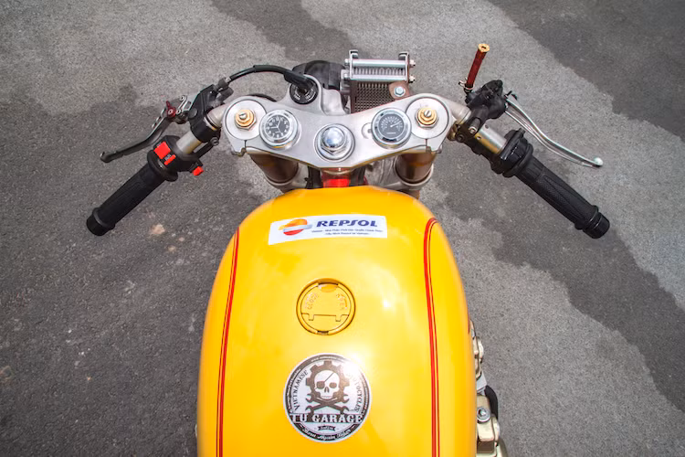 Theo đúng phong cách cafe racer, chiếc xe đã được trang bị cặp tay lái clip-on thấp đầy thể thao. Khác với những bản độ trước đây của xưởng độ Tự Thanh Đa, chiếc CB750 này hoàn toàn không có công tơ mét, thay vào đó trên chảng ba của xe chỉ có đồng hồ báo giờ và báo nhiệt độ ngoài trời. Ở hai bên, cùm công tắc của chiếc xe cũng được rút gọn.