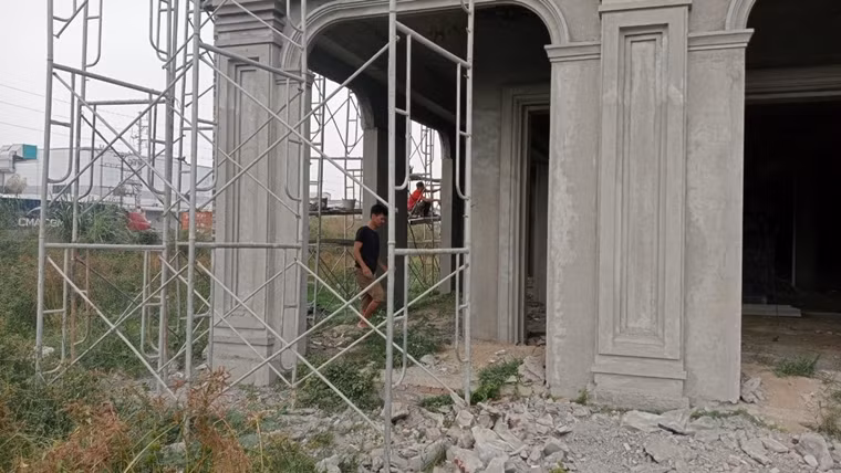 Các công nhân leo giàn giáo làm việc ngay sát đường điện cao thế.