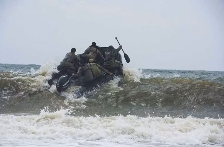Xuồng cao su chở đội viên Biệt đội đặc nhiệm Vệ binh Quốc gia Hoa Kỳ đang vượt cơn sóng dữ tiến ra biển.