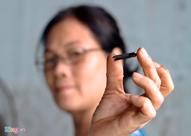Khu chợ hàng "nghĩa địa" có nhiều loại sản phẩm khác nhau. Trong ảnh, chủ cửa hàng kinh doanh máy may cũ vừa tìm được một chi tiết máy trong kho hàng để đáp ứng nhu cầu của khách.