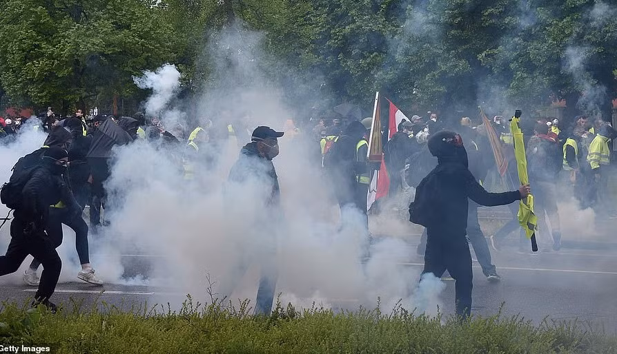 Những người thuộc phong trào Áo vàng bịt kín mặt giữa làn khói hơi cay mù mịt. Ảnh: Getty.