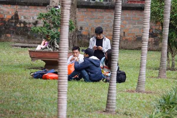 Trong lúc chờ đợi đến lượt được “phó nháy” đưa vào hình, nhiều sinh viên ngồi lên bãi cỏ trong khuôn viên Văn Miếu - Quốc Tử Giám để ăn uống.