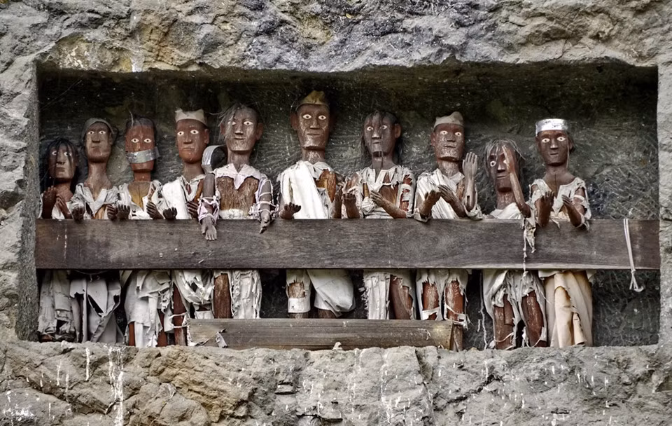  Hình nộm người chết (Tau Tau): Cũng là một truyền thống từ Tana Toraja, Tau Tau là hình nộm chạm khắc từ gỗ hoặc tre đại diện cho người đã chết, thường giống người đó và có thể tìm thấy gần mộ. Người Toraja tin rằng linh hồn của người chết sẽ tiếp tục sống qua Tau Tau và phục vụ như người bảo vệ ngôi mộ. Ảnh: Indoindians.