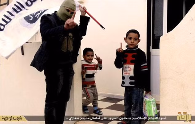 Một lính IS mang lá cờ của tổ chức tạo dáng cùng 2 trẻ em ở thành phố Benghazi, Libya. Tổ chức giám sát nhân quyền (Human Rights Watch), một tổ chức bảo vệ nhân quyền của mọi người trên toàn thế giới, cho biết binh lính IS đã tuyển dụng trẻ em, gửi chúng vào trại huấn luyện quân đội và sử dụng chúng trong những hoạt động bao gồm cả đánh bom liều chết.