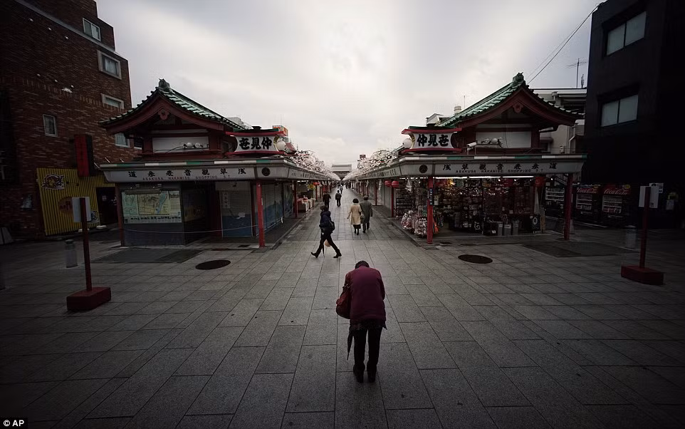 Cũng con phố Naakamise ngày nay ở quận Asakusa, Tokyo. Nơi đây vẫn là con phố mua sắm như ngày nào nhưng đã mang nhiều nét khang trang, hiện đại hơn. Trong hình là một du khách đang cầu nguyện hướng về phía ngôi đền Sensoji.