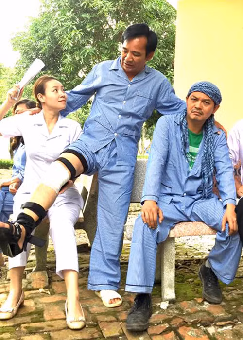 Quang Tèo úp mở hình ảnh nhân vật Sự của mình phải băng bó chân phải trong trang phục của một bệnh nhân ở trại nuôi dưỡng người tâm thần. (Ảnh: Facebook nhân vật)