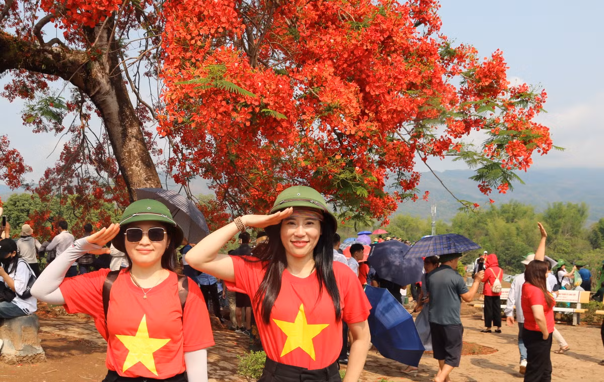Các bạn trẻ mặc áo cờ đỏ sao vàng chụp ảnh kỷ niệm bên hoa phượng khi tới thăm đồi A1.