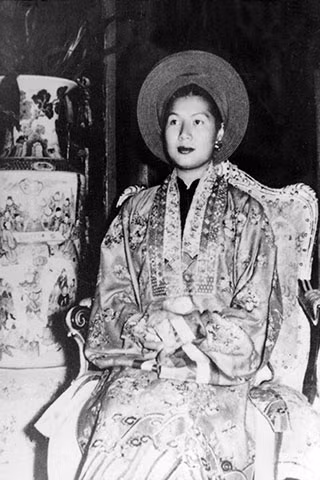 Ngay cả chữ Hán trang trí trên áo mão cũng có sự phân biệt. Áo vua thêu nổi các chữ Phúc, Lộc, Thọ đại tự theo lối chữ triện, trong khi các chữ Phúc, Lộc, Thọ trên áo phụ nữ thường nhỏ hơn và dệt chìm trên mặt vải, không nạm trân châu hay thêu kim tuyến như trên áo mũ của vua và thường thể hiện theo lối chữ chân. Ảnh: Hoàng hậu Nam Phương trong trang phục thường triều.
