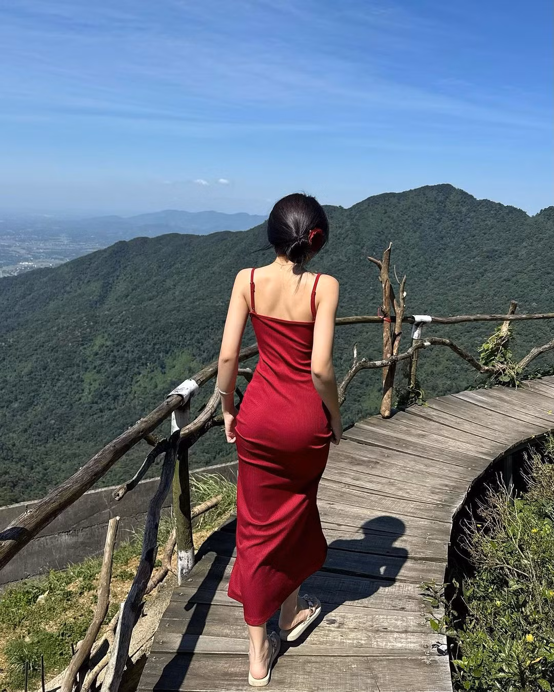 Diện chiếc váy hai dây màu đỏ nổi bật, nữ Tiktoker khoe dáng giữa khung cảnh mộng mơ, phía sau là rừng núi.