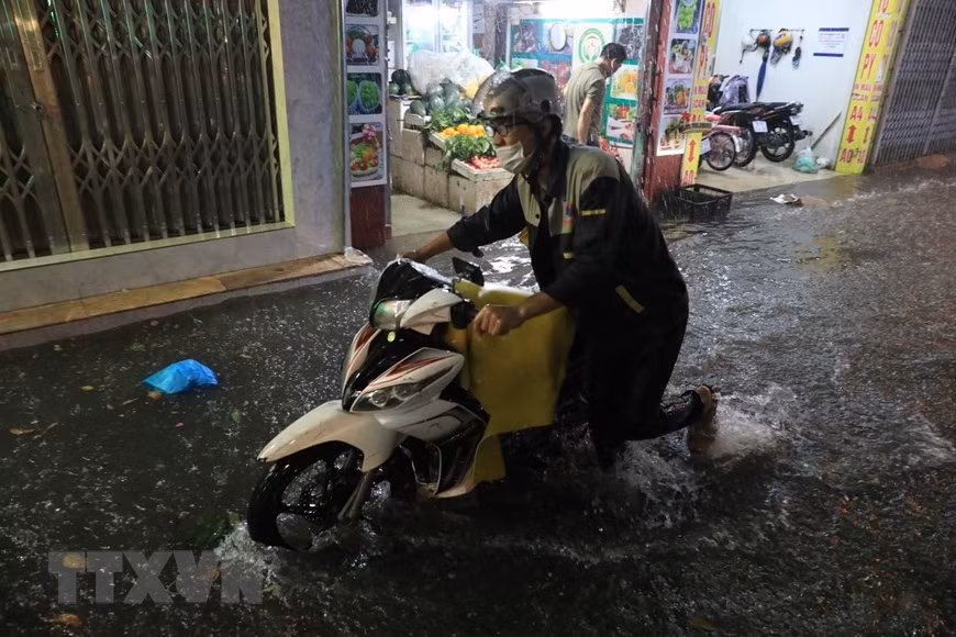 Nhiều người phải dắt xe qua đoạn ngập. (Ảnh: Tuấn Anh/TTXVN)
