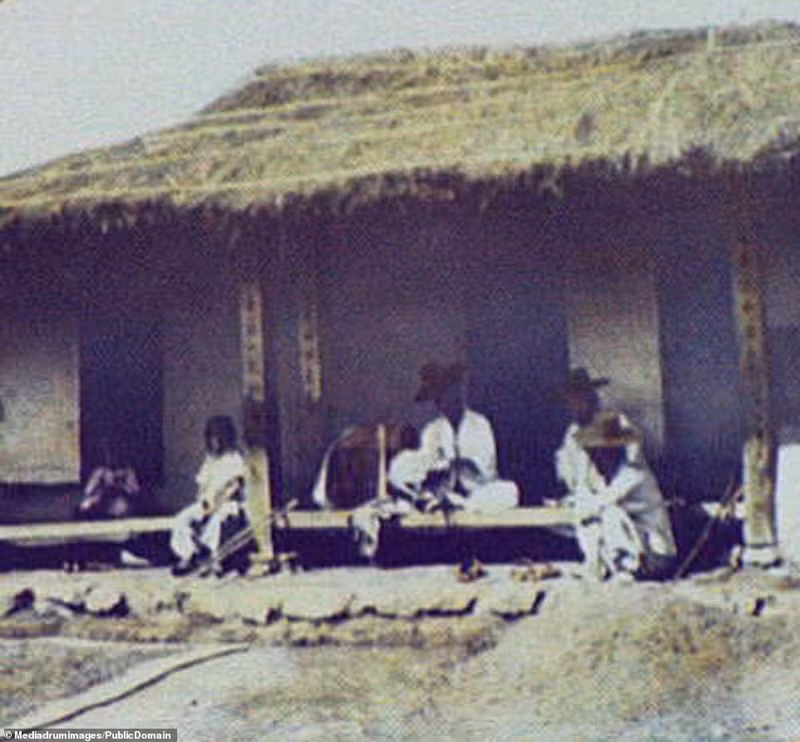 Gia đình một người dân địa phương đang ngồi trò chuyện trước hiên ngôi nhà lá đơn sơ.
