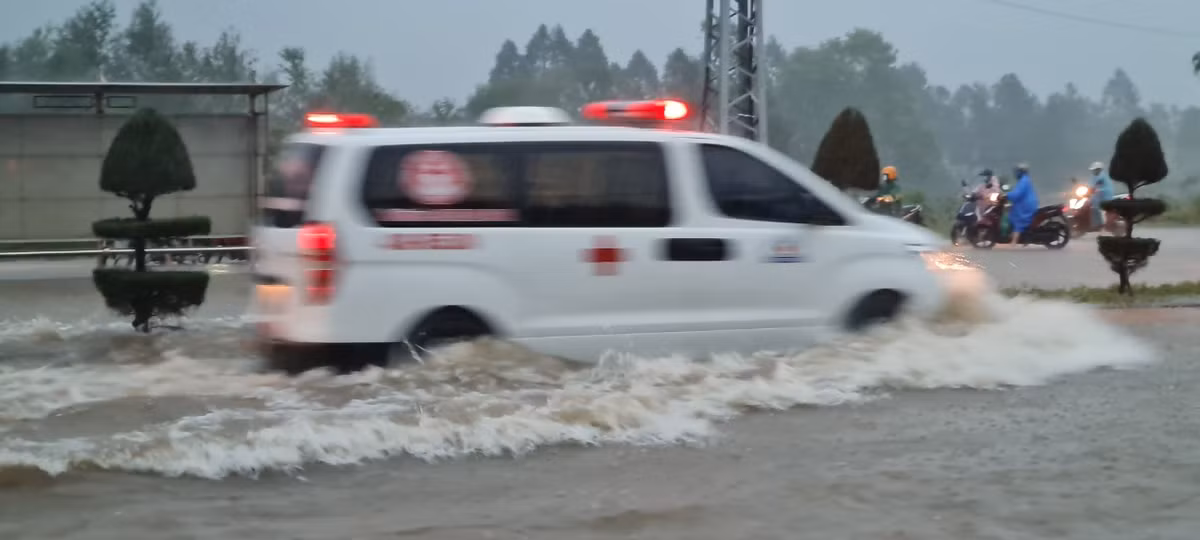 Một chiếc xe cấp cứu chạy băng băng giữa cơn mưa trắng trời.
