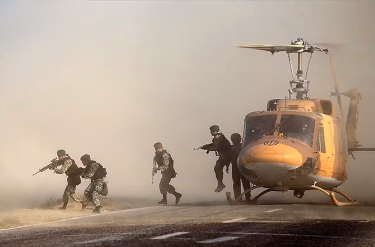 Trực thăng Bell 214A vận chuyển đội chống khủng bố của Lữ đoàn Đặc nhiệm không kỵ 65 của quân đội Iran bay sát đất khiến cát bay mù mịt.