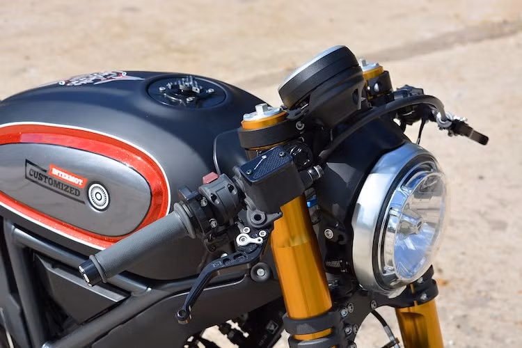 Cặp phuộc Ohlins FGRT trước của xe được lấy từ Ducari 1199R Panigale nhưng được cắt ngắn để giữ khoảng hành trình như trên Scrambler gốc. Bộ mâm 17 inch 5 cánh xoắn của hãng OZ dành riêng cho Ducati 899 đã được "phẫu thuật" sang Scrambler, cùng với hệ phanh đĩa với cặp heo Brembo M50 cũng từ 1199 Panigale.