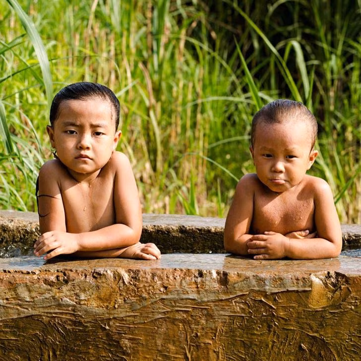 Hai em bé ở vùng nông thôn Việt Nam tắm mát giữa ngày Hè.