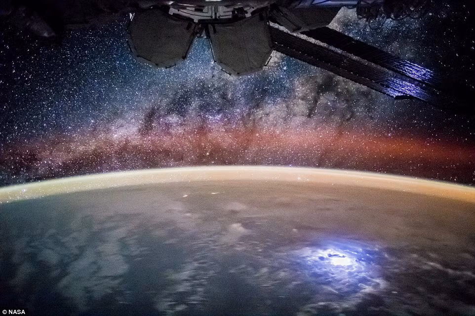 Một tia sét bất ngờ lóe sáng làm hiện vòng xoáy bão dưới Trái đất. Phía trên là thiên hà Milky Way khoe sắc. Nguồn ảnh: Dailymail.
