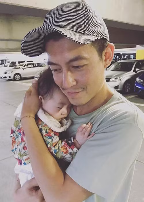 Hình ảnh Trần Quán Hy mỉm cười, ôm con gái vào lòng.