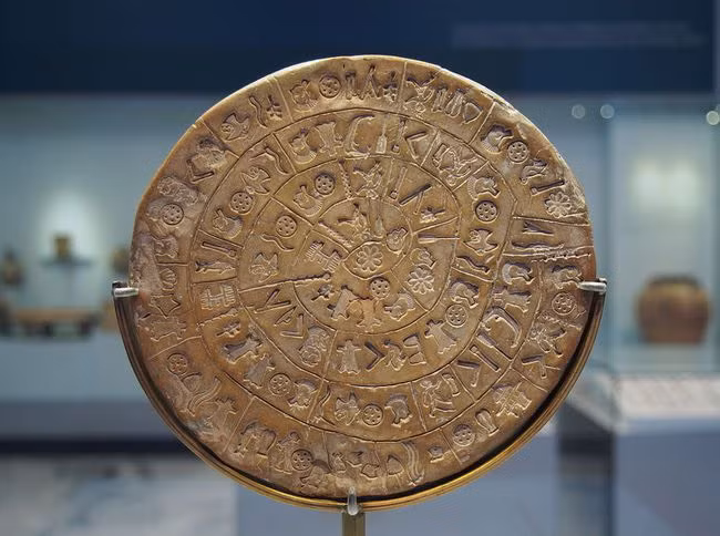 Đĩa Phaistos được phát hiện bởi nhà khảo cổ học người Ý Luigi Pernier vào năm 1908 tại cung điện Minoan của Phaistos, chiếc đĩa được làm bằng đất sét nung và chứa các biểu tượng bí ẩn có thể đại diện cho một dạng chữ tượng hình chưa được biết đến. Theo các nhà khảo cổ, nó có thể ra đời vào thế kỷ 2 TCN. Nguồn: C messier/Wikimedia Commons.
