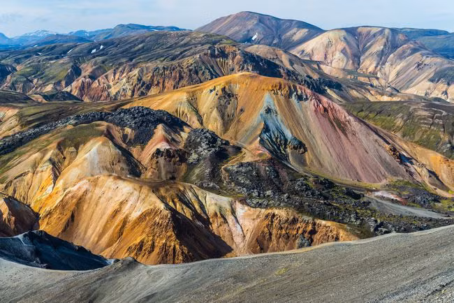 Landmannalaugar là một vùng nội địa Iceland, các đỉnh núi ở đây chủ yếu có màu xám đậm hoặc đen, nhưng cũng có những vệt màu xanh lam, hồng và cam. Chúng được cấu tạo từ đá ryolit, một loại đá núi lửa thường xuất hiện thủy tinh do hàm lượng silica cao. Nguồn: Fibru Photography/Getty Images.