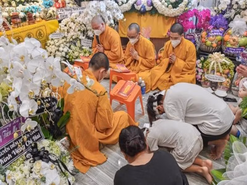 Hồ Văn Cường đội khăn tang, cúi đầu khấn mẹ nuôi. Ảnh: Yan