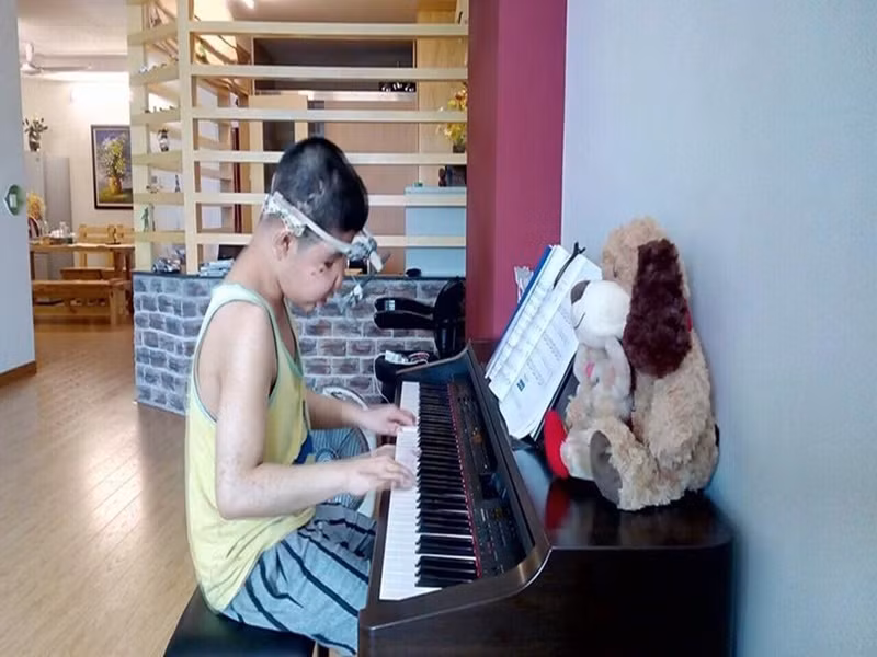 Từ lúc 1- 2 tuổi, Bôm đã tỏ ra thích thú với piano. Sau khi phẫu thuật bàn tay, con trai Quốc Tuấn rất chăm chỉ luyện đàn theo chương trình của nhạc viện. Âm nhạc không chỉ là niềm đam mê mà còn giúp Bôm quên đi những đau đớn vì bệnh tật. Ảnh: Vietnamnet.