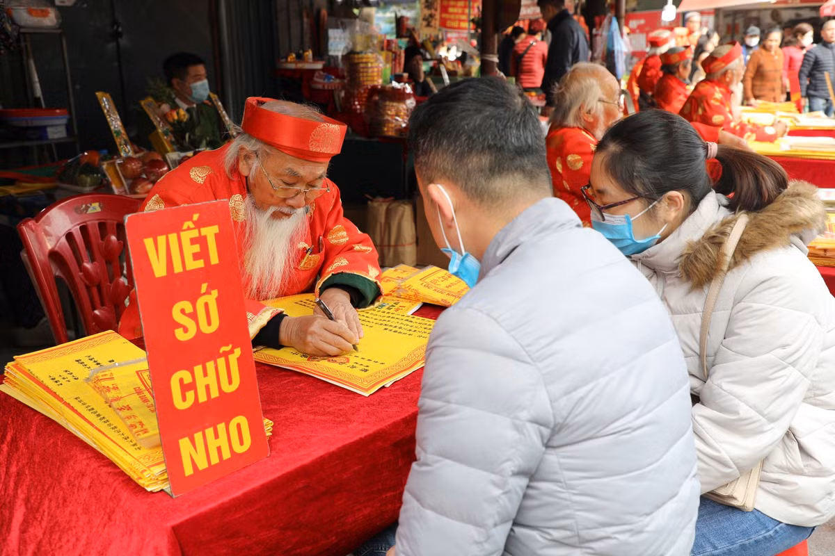 Du khách viết sớ ở cổng phủ trước khi vào làm lễ.