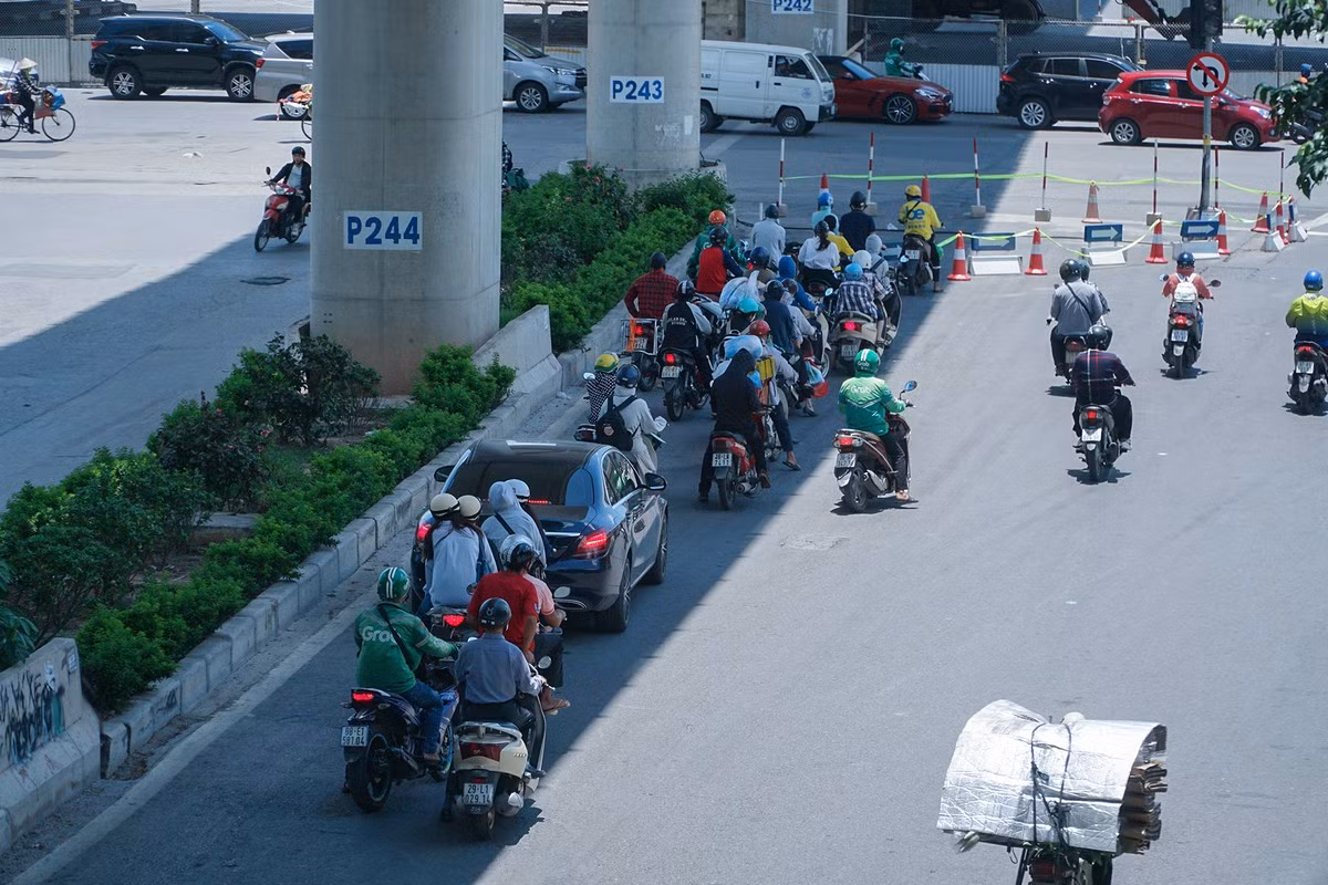 Trên đường Xuân Thủy, các phương tiện tận dụng bóng mát của đường sắt Nhổn - ga Hà Nội trong lúc chờ đèn đỏ.