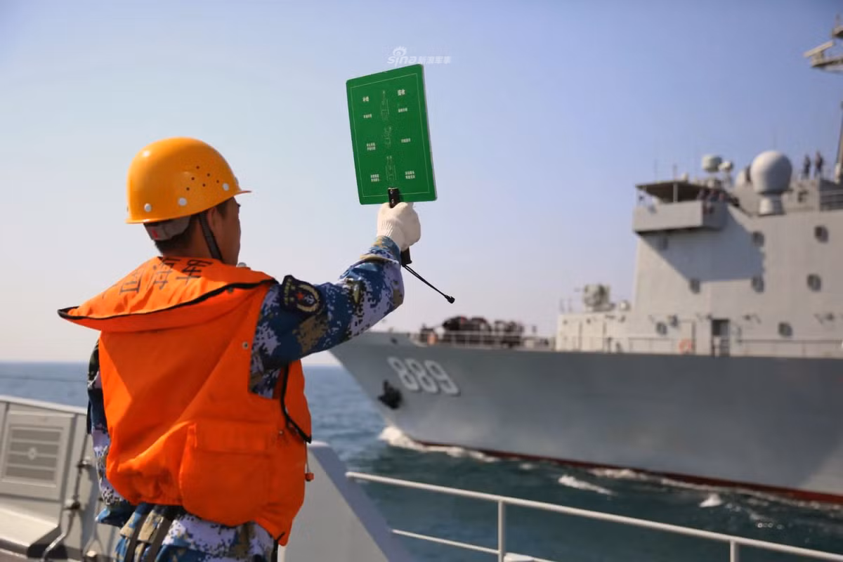 Ảnh: Thủy thủ tàu Type 054A ra ám hiệu liên lạc với tàu vận tải hậu cần số hiệu 889 đang di chuyển song song.