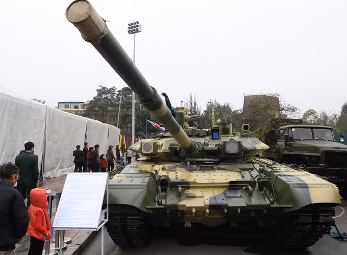 Thứ hai, về hệ thống bảo vệ, T-90 S/SK có phần nhỉnh hơn với việc được trang bị hệ thống phòng thủ chủ động Shtora-1-M với đặc trưng là cặp đèn gây nhiễu tên lửa chống tăng (ATGM) thế hệ 1 &amp; 2 mang tên OTShU-1-7-M và các cảm biến laser đặt xung quanh tháp pháo. Ảnh: Tháp pháo xe tăng T-90 S/SK Việt Nam với cặp đèn nhiễu OTShU-1-7-M.