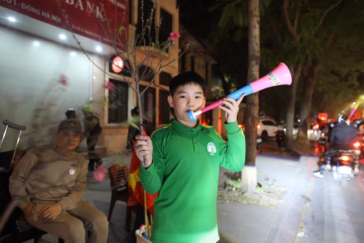 Những em bé cũng hoà nhập vào không khí "đi bão". Hoa đào và âm thanh kèn càng tô điểm cho sự cuồng nhiệt của các cổ động viên.