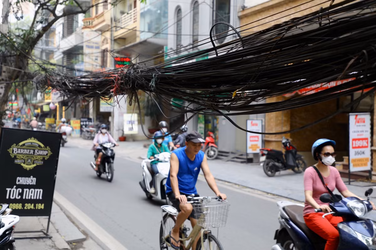 Ghi nhận của PV, tại phố Định Công (quận Hoàng Mai, Hà Nội) những bó dây điện, cáp viễn thông nặng trĩu, sà xuống mặt đường, gần chạm đầu người đi bộ.