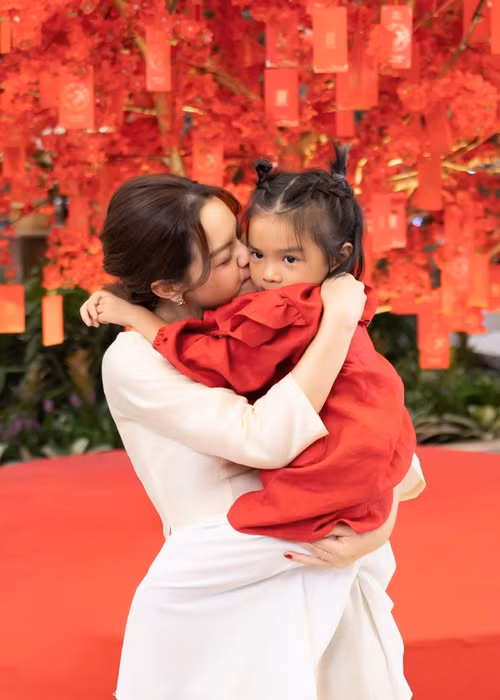 Bé Tuệ An diện áo dài đỏ, búi tóc tinh nghịch.