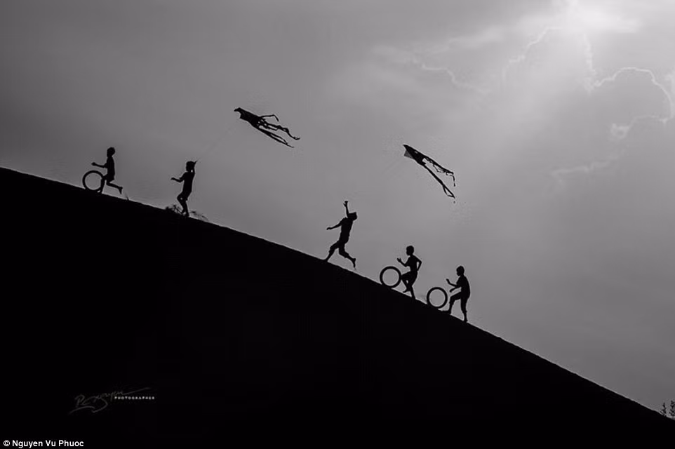 Những đứa trẻ thả diều trên cát trong một buổi chiều lộng gió.