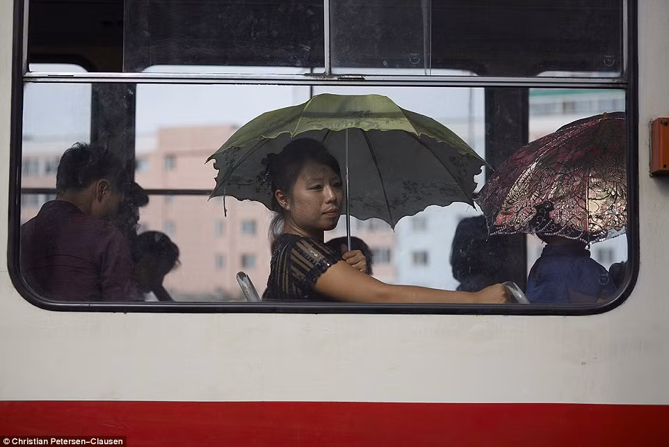 Các hành khách nữ vẫn phải dùng ô để che nắng khi ngôi trên xe bus.