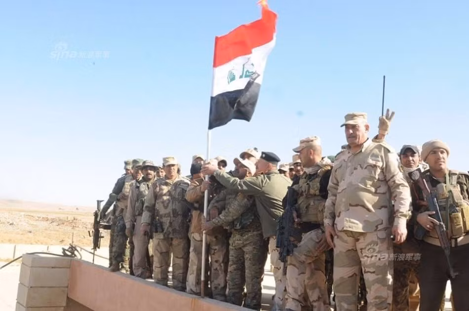 Sĩ quan và binh lính Iraq đang cắm cờ chiến thắng tại một cứ điểm.