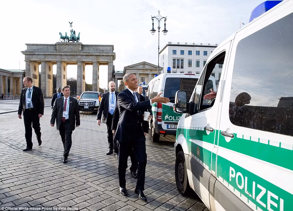 Sau khi kết thúc các cuộc họp trong khuôn khổ hội nghị tổ chức ở Berlin, Đức ngày 17/11, Tổng thống Obama quyết định đi bộ về khách sạn. Trong ảnh, ông Obama bắt tay với cảnh sát Berlin ở gần Cổng Brandenburg. Ảnh Daily Mail