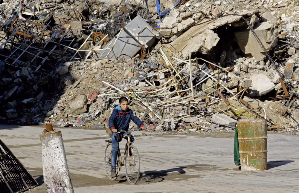 Một bé trai Syria đạp xe qua đống đổ nát ở Aleppo hôm 22/1, một tháng sau khi lực lượng chính phủ Damascus giải phóng hoàn toàn thành phố này khỏi tay các nhóm phiến quân.