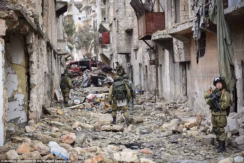 Các binh sĩ Nga đi qua con phố ngổn ngang gạch vỡ ở thành phố Aleppo mới giải phóng.