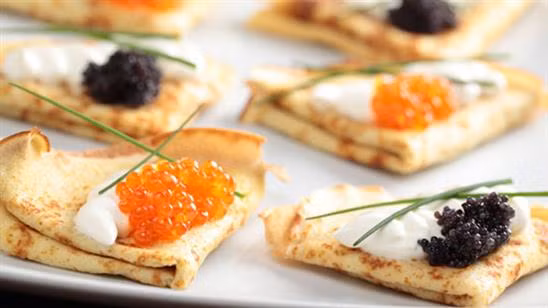 Bánh Blini: Đến Nga, bạn có thể thưởng thức món bánh đặc trưng này ở bất cứ con phố nào. Blini tròn rắn được nấu trên các vỉ nướng với nguyên liệu ăn kèm như thịt nguội, phô mai hoặc trứng cá muối đỏ.