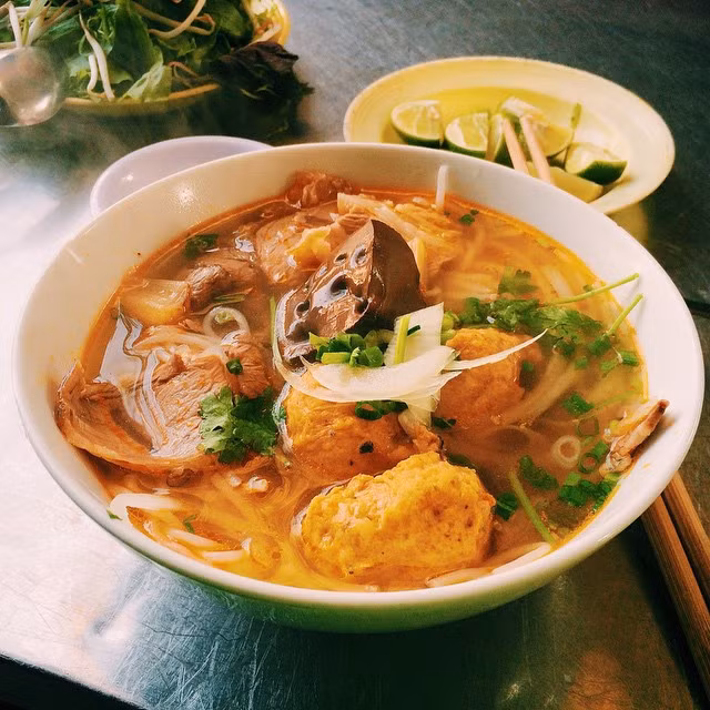 Nước lèo được nấu trong nồi nhôm đáy tròn, cổ eo, thân phình đúng kiểu Huế, thơm mùi sả. Ngoài bò bắp, bò tái, giò heo, tô bún ở đây còn có chả cua, chả tôm do quán tự làm. Ăn kèm bún là đĩa rau thơm, tía tô, bắp chuối... hợp khẩu vị người miền Nam. Địa chỉ: 113 Bà Huyện Thanh Quan, quận 3. Mức giá trung bình: 50.000 đồng. Ảnh: @quinbeo, @rosebennet.