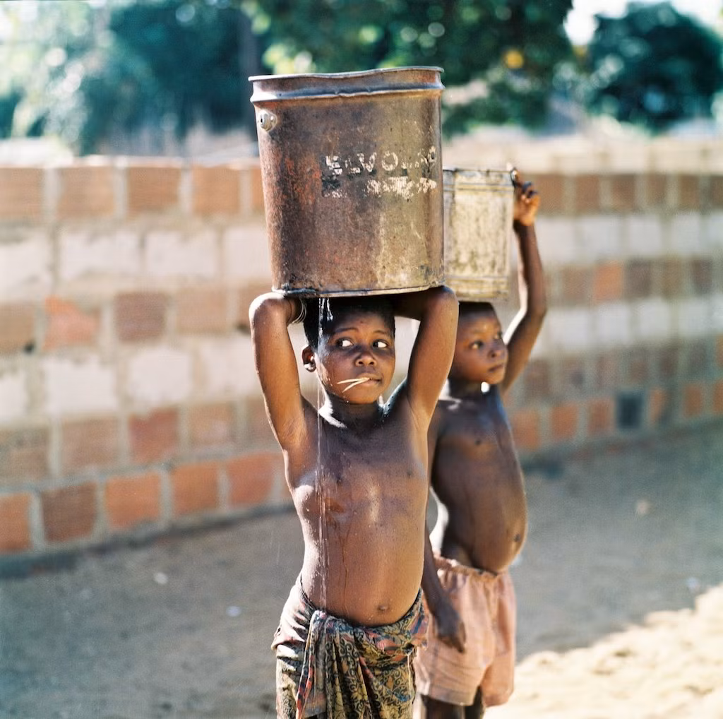 Hai cậu bé Mozambique gánh nước phụ giúp gia đình. Ảnh: Thomasbillhardt.de.