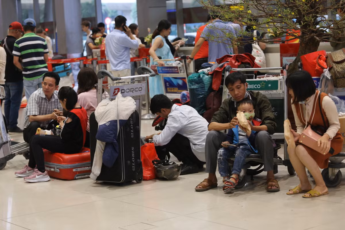 Người lớn, trẻ nhỏ ngồi la liệt khắp sảnh sân bay để chờ làm thủ tục.