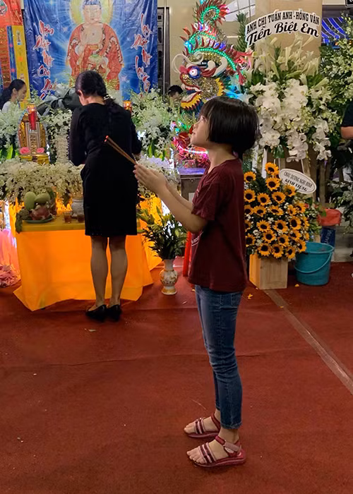 Bé Nguyệt Cát thắp nén nhang cho nghệ sĩ Anh Vũ. Ảnh: FBNV
