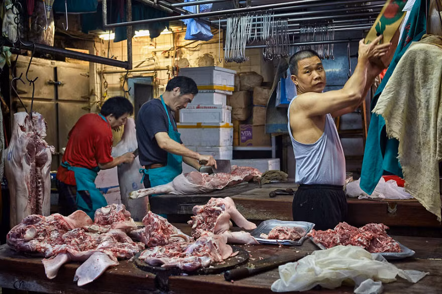 Ba người đàn ông đang chuẩn bị bày bán thịt lợn trên phố Bowrington.