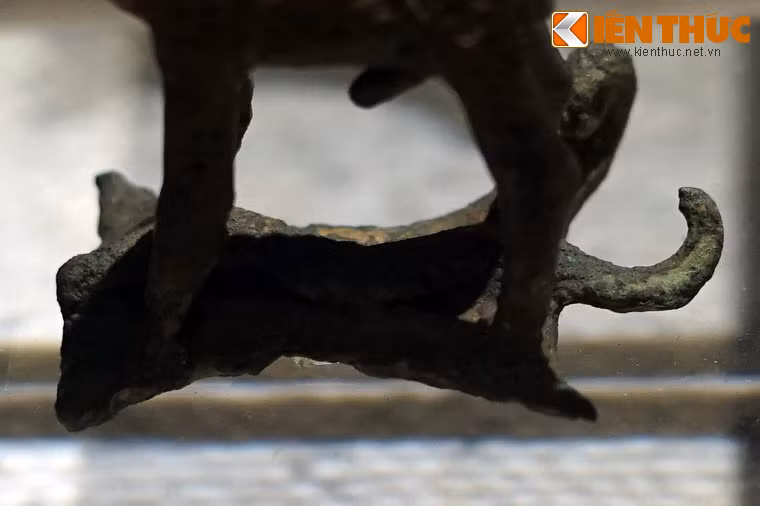 Dưới bốn chân con vật có chiếc đế hình động vật, đã bị gãy đầu. Về con vật nằm ở dưới này, có nhiều ý kiến đây là loài bò sát (rắn hoặc trăn). Còn Tiến sĩ khảo cổ Vũ Thế Long lại cho đó là con chồn dơi, còn con vật đứng trên là chó săn.