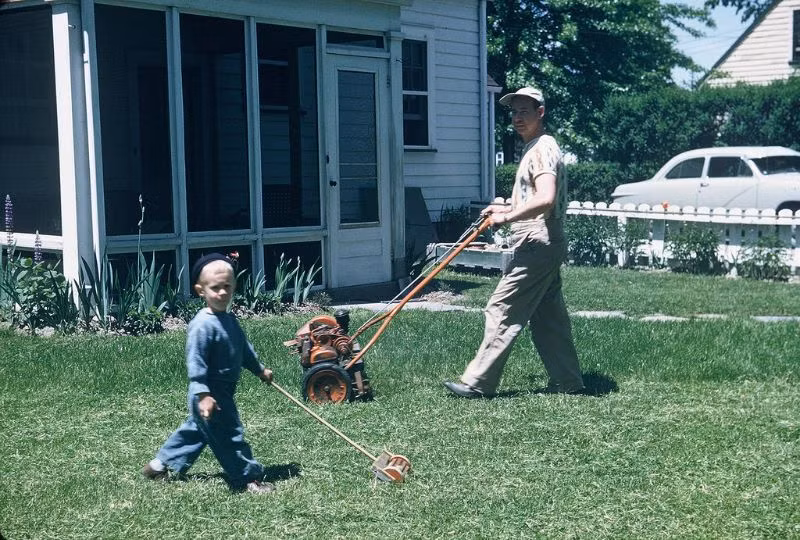 Em bé phụ bố cắt cỏ trước sân nhà ở bang Ohio, 1951. Ảnh: Walter Reed.